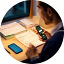 Graduate entrepreneur working at a small desk with invoices and a phone
